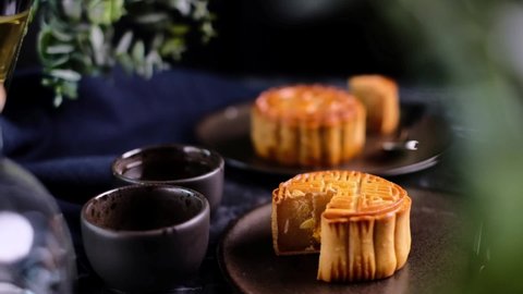 Moon cakes with Chinese tea pouring. Mooncake is a traditional Chinese bakery. Often eating on Mid-Autumn Festival or lunar appreciation festival. Moon cakes festival concept. Dark food photography.