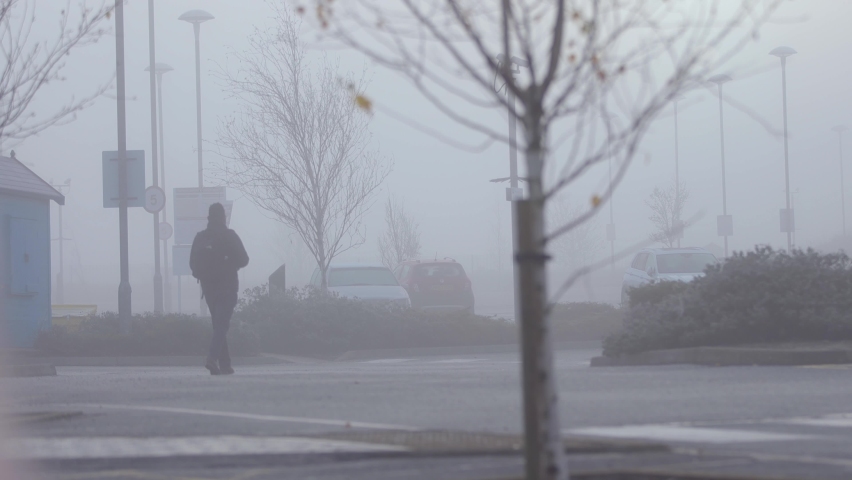 Lonesome commuter walks across car park in the morning fog