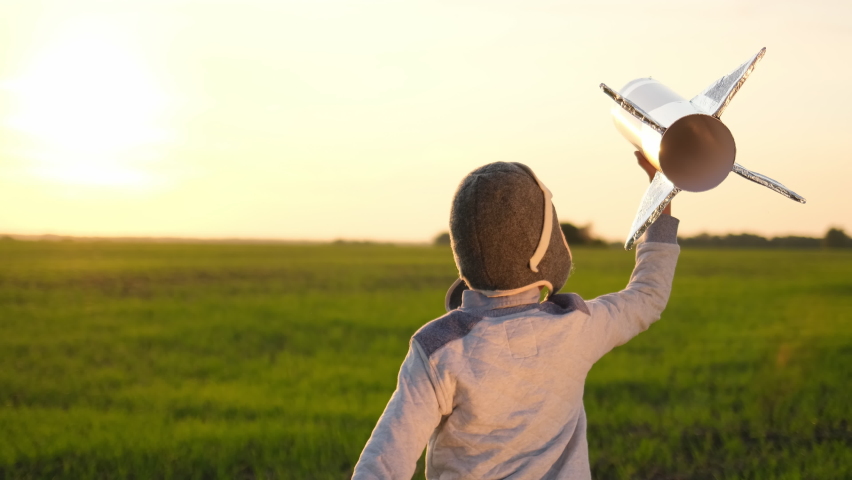 Happy little boy child in helmet aviator cosmonaut walking with toy rocket in sunset field summer nature. Kid big dream flying, astronaut, space, Concept of success leader winner, travel freedom, 4 K Royalty-Free Stock Footage #1063628128