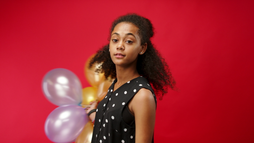 Young teenager girl in a studio on red background, looking at camera.