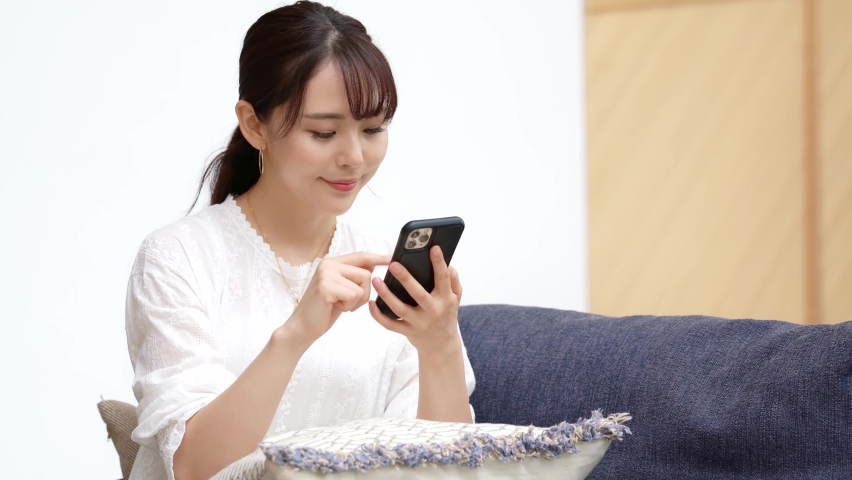 Young asian woman using a smart phone in the room. Royalty-Free Stock Footage #1063636387