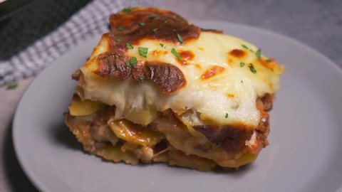 Traditional Greek moussaka - potato and meat casserole with cheese, dark background. Greek food concept.