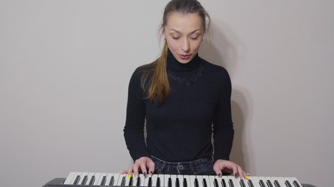 Young pretty woman teaching to play on synthesizer in online video classes, live streaming concept. Piano lessons for begginers, practicing music instrument at home, blogging, vlogging, study concept