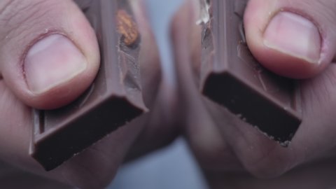 Woman hands breaks chocolate bar.  Hands break a bar of chocolate. Closeup.