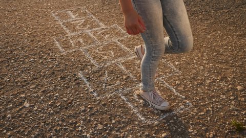girl child playing classics hopscotch game in the park. childhood kid dream concept. little girl jumping on the squares game hopscotch. kid playing outdoors dream of happiness fun