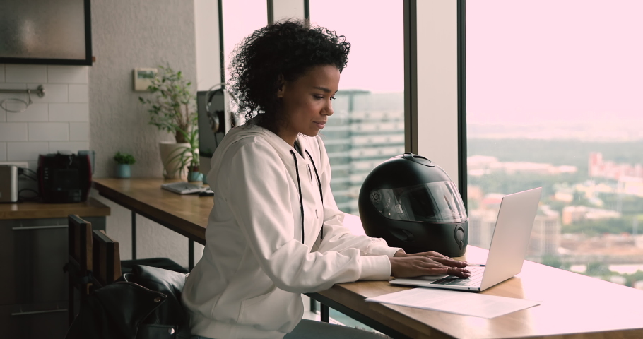 Pensive serious african 35s freelancer woman sit at table in modern office room alone working using laptop looking out the window thinking over business issue solution make telecommute job from home Royalty-Free Stock Footage #1063642360