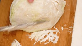 Female hands cut with knife white cabbage on wooden cutting board on kitchen