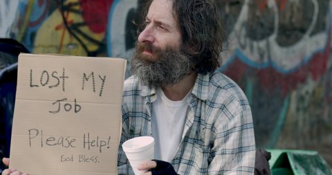 Woman gives money to an unemployed homeless man panhandling for help with a cardboard sign that says lost my job please help