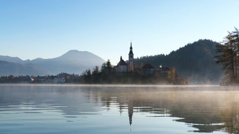 Beautiful soft video of Bled lake landscape with view of the Saint Martin Church at autumn morning in fog, Bled, Slovenia.