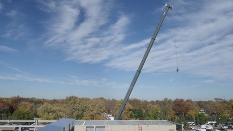 Time-lapse of Construction Site Large Industrial Crane Working on roof of building With Workers with lovely Autumn trees and wispy clouds.