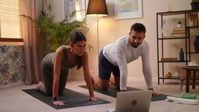 Young Caucasian Man And Woman Couple In Sportswear Doing Sports At Home On Mat While Watching Fitness Video Online On Laptop. Stay Home Quarantine Workout Training, Workout And Wellness Concept.