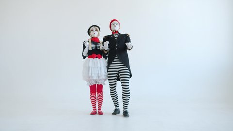 Crazy mime artists male and female driving imaginary car gesturing making funny faces against white background. Pantomime and transport concept.