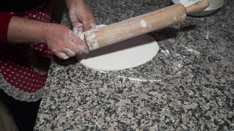 A woman is rolling the dough for baklava with rolling pin