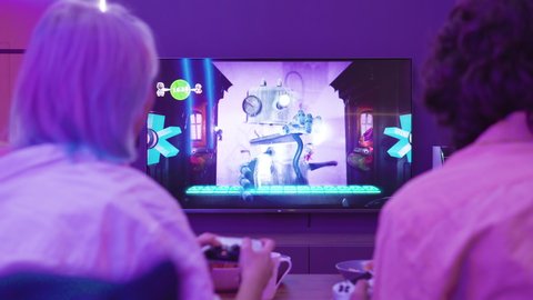 Back view of young couple play video game Sackboy Little big Planet on a Xiaomi Mi TV using PlayStation 5 gaming console. Moscow - November 28 2020.