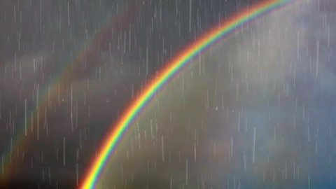 Noisy Rain Falling On Rainbow Time Animation Loop Footage. Monsoon Rain Storm Clouds With Beautiful Colourful Rainbow Cloudy Dark Sky Background.