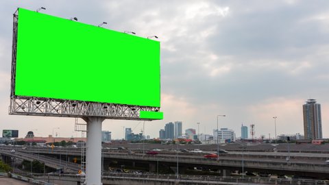 Green screen of advertising billboard on expressway during the sun beams shining through moving dramatic rain clouds with city background in Bangkok, Thailand. Time lapse