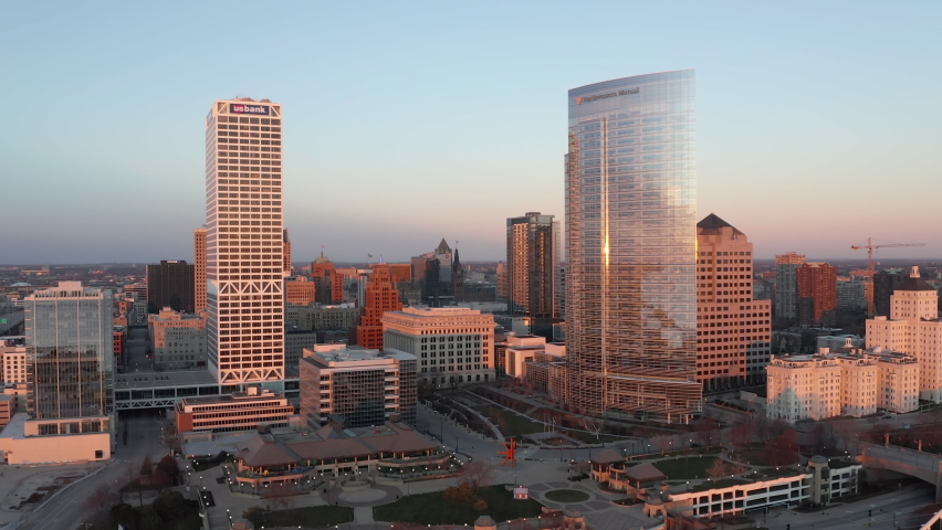 Aerial reverse shot of Downtown Milwaukee at sunrise. Tall buildings by the lake