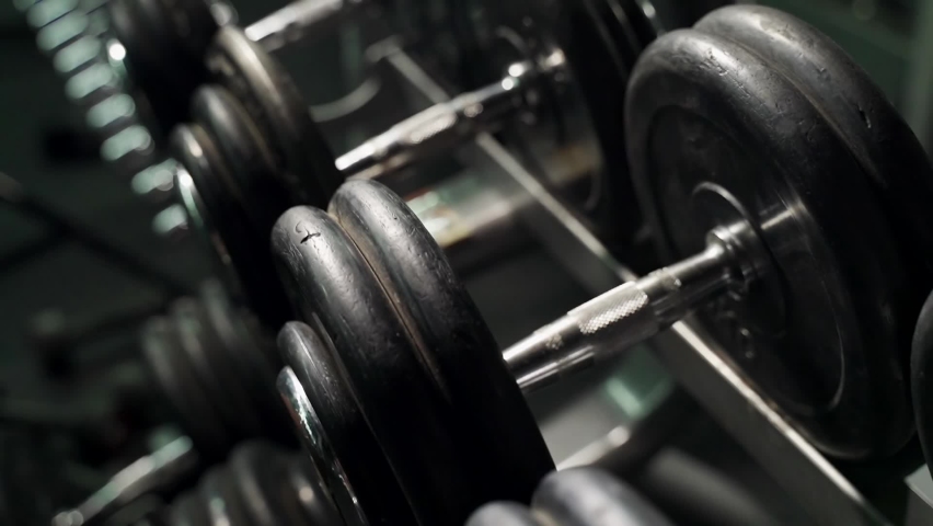 Rack with dumbbells in the gym. The movement of the camera along the rack with dumbbells | Shutterstock HD Video #1063680349