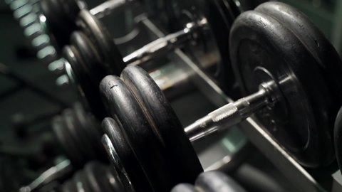Rack with dumbbells in the gym. The movement of the camera along the rack with dumbbells