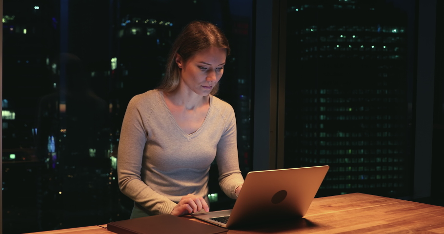 Serious workaholic business lady work until late in modern office room, female sit at desk using laptop solve issues, feel tired overload by over hours job at workplace, night city view through window Royalty-Free Stock Footage #1063684069