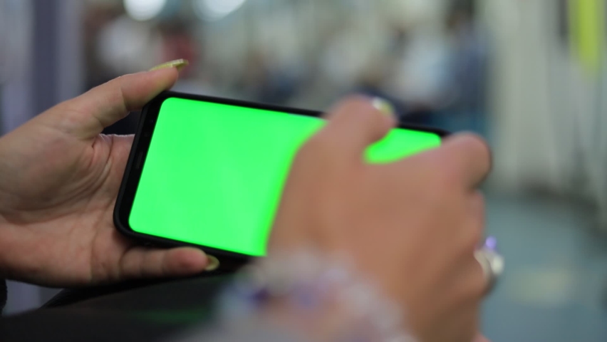 Female hands are holding a smartphone and touching the screen with their fingers. On-screen green rear background. | Shutterstock HD Video #1063691164