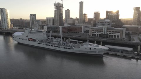 Liverpool , Merseyside , United Kingdom (UK) - 05 26 2020: RFA Navy Tiderace military tanker on Liverpool cityscape waterfront at sunrise slow rising aerial view