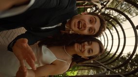 Pov shot of newlyweds man and woman having video call in park. Closeup happy couple informing about marriage outdoors. Brunette bride sending kisses on camera in vertical orientation