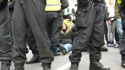 LONDON, UNITED KINGDOM - 28, NOVEMBER,2020: In the middle of Regent Street riot police officers wearing helmets and face masks holding two young women handcuffed, one on the ground another is standing