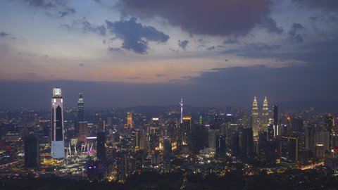 Time lapse: Aerial cityscape view before dusk overlooking the Kuala Lumpur city center skyline and construction area at sunset in Malaysia. Day to night. High Quality Prores 4K