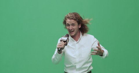Studio, slow motion, green screen, young male reporter against the wind, London, UK