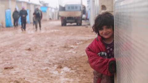 A refugee girl laughs despite the very cold weather in the rain.
Aleppo, Syria 16 December 2018