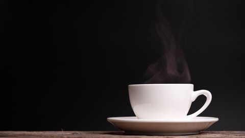 Coffee cup with natural steam smoke of coffee on dark background with copy space, slow motion. Hot Coffee Drink Concept.