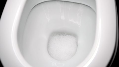 Flush the toilet close-up. White clean toilet, flushing water large, 4K video.