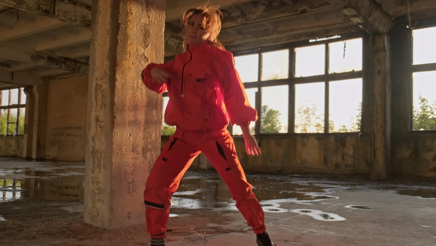 Talented fermale dancer dancing in factory building. Brunette in orange wear dancing hip-hop. Woman enjoying modern dance during sunset. 4K, UHD | Shutterstock HD Video #1063716238