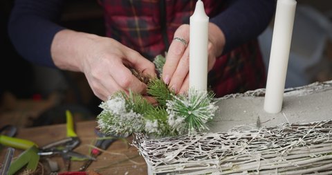 Close up shot of a woman florist decorator making a beautiful holiday basket with candles