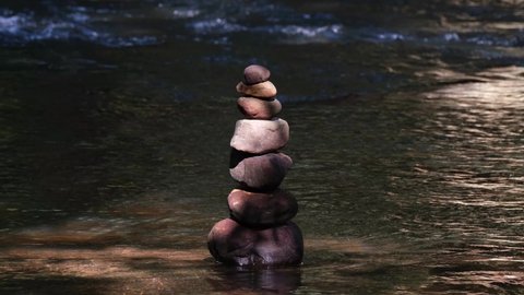 Rock Balancing or Rock Stacking in the middle of the river; long 4K footage perfect for making relaxing ASMR videos with natural ambience or relaxing music to meditate or for sleeping.
