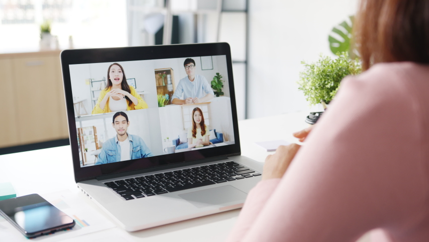 Young Asia businesswoman using laptop talk to colleague about plan in video call meeting while work from home at living room. Self-isolation, social distancing, quarantine for corona virus prevention. | Shutterstock HD Video #1063723309