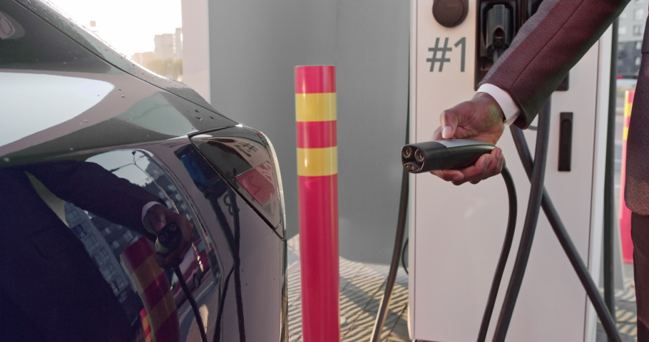 Start of a refueling process of an electric car. A shot under the hatch where the electric eco car charges. The electric car charging hatch opens automatically. A male hand inserts an erectile car Royalty-Free Stock Footage #1063723984