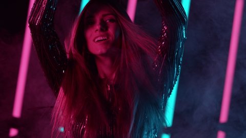 Slow motion of young woman dancing with neon lights background. Filmed on high speed cinema camera.