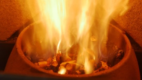 Close-up of burning flames inside the modern pellet stove, yellow and orange fire burning and heating building. Alternative and economical biofuel, power and energy concept. Heated pellet stove