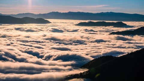 Low clouds flow like a river in alpine mountains valley in beautiful autumn nature landscape Time lapse