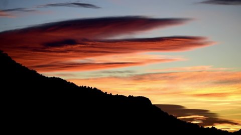 Sunset over mountains. Time-lapse of sun setting over the mountains. Sequence of clouds forming and dissipating near sunset passing by over the sky in Time Lapse at colorful sun set in Spain