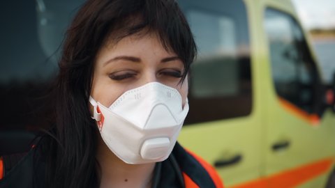 Macro eyes view: Female paramedic looks at you near ambulance vehicle