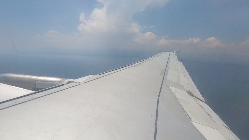 View from the window of the illuminator. The plane makes a turn and tilts the wing. Sunny. Clouds are visible in the sky. Royalty-Free Stock Footage #1063732921