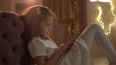 A little girl writes a letter to Santa Claus on her smartphone