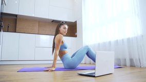 Lockdown activities. Millennial girl following workout video tutorial in her home training. Beautiful young woman training online at home on laptop computer. Yoga, pilates, working out exercising