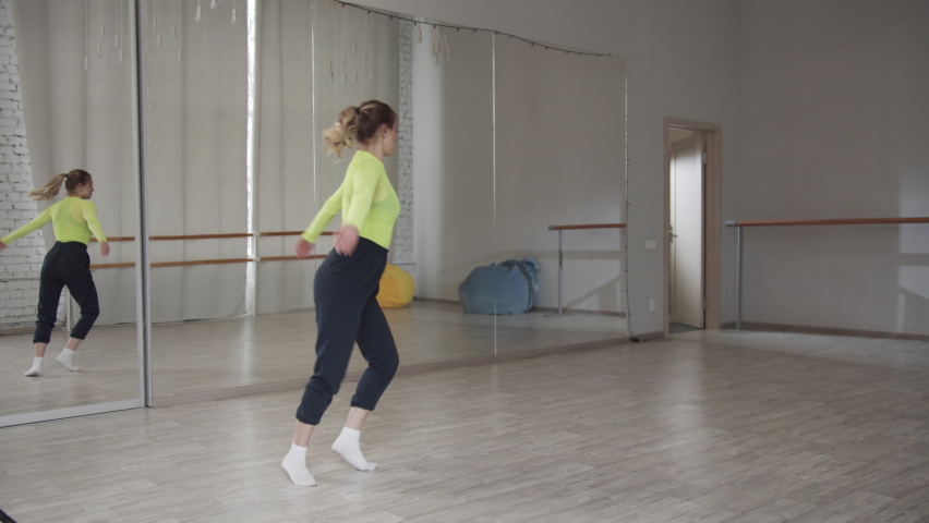 Slow motion. Sporty pretty blonde girl does an acrobatic somersault in a dance hall with a mirror .