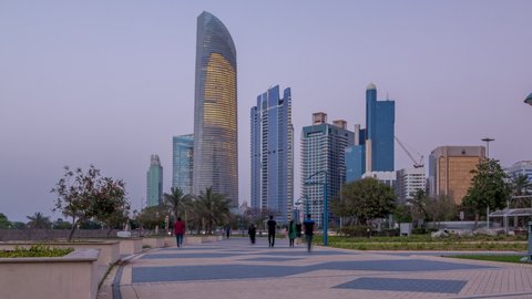 Skyscrapers in Abu Dhabi Skyline day to night transition timelapse, United Arab Emirates. View from Corniche with illuminated modern towers