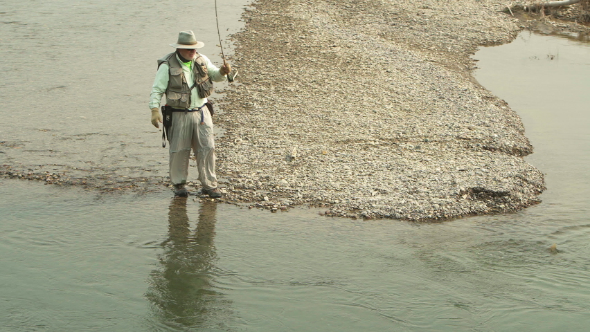 Fisherman lets the hooked fish tire itself out as it splashes in the Buffalo Fork River, Bridger-Teton National Forest, Wyoming. Static shot.