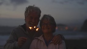 new year. close up of seniors celebrating the new year together at the beach with sparklers lights - Powered by Shutterstock - Get 15% off with code: PIKWIZARD15